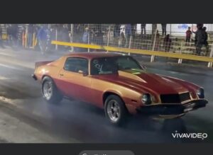 Orange classic muscle car doing burnout on dragstrip
