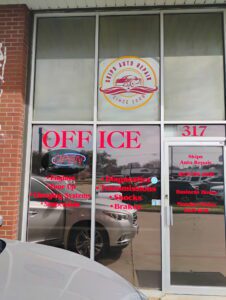 Auto repair storefront with logo and reflected car